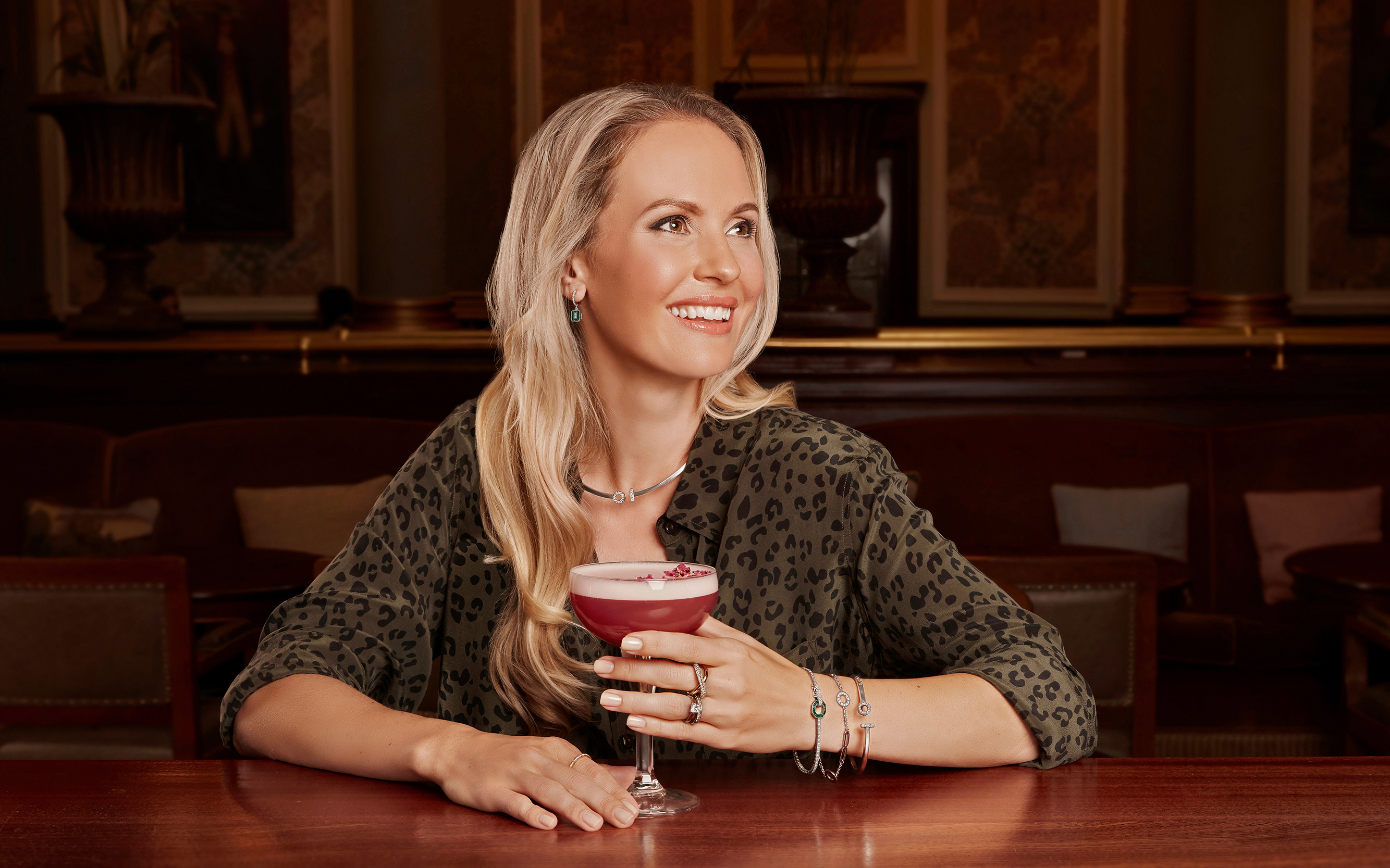 Model sitting at a bar smiling drinking a cocktail on a jewel advertising photo shoot in norwich