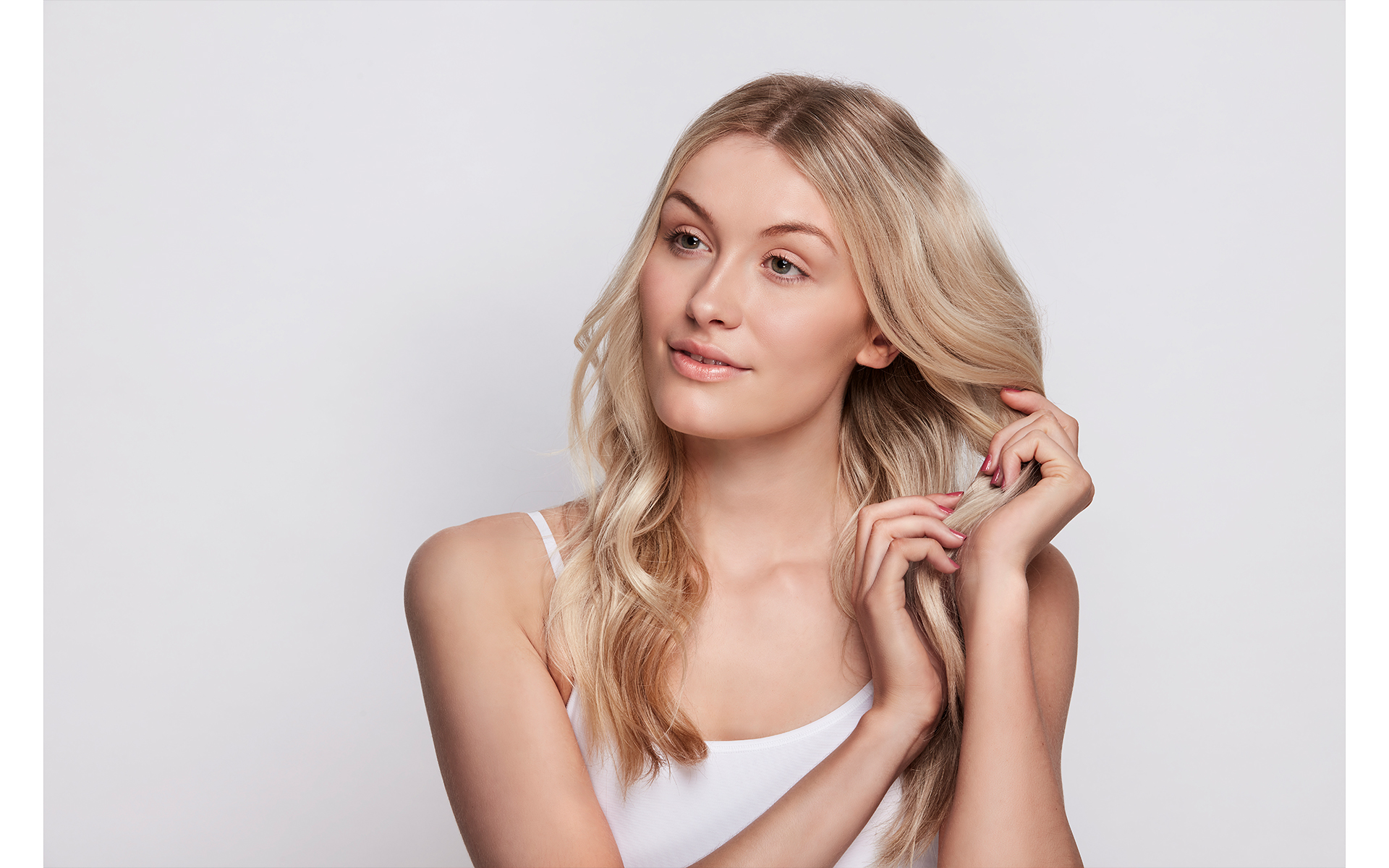 Blonde model playing with her hair on a beauty photo shoot front of a white back drop