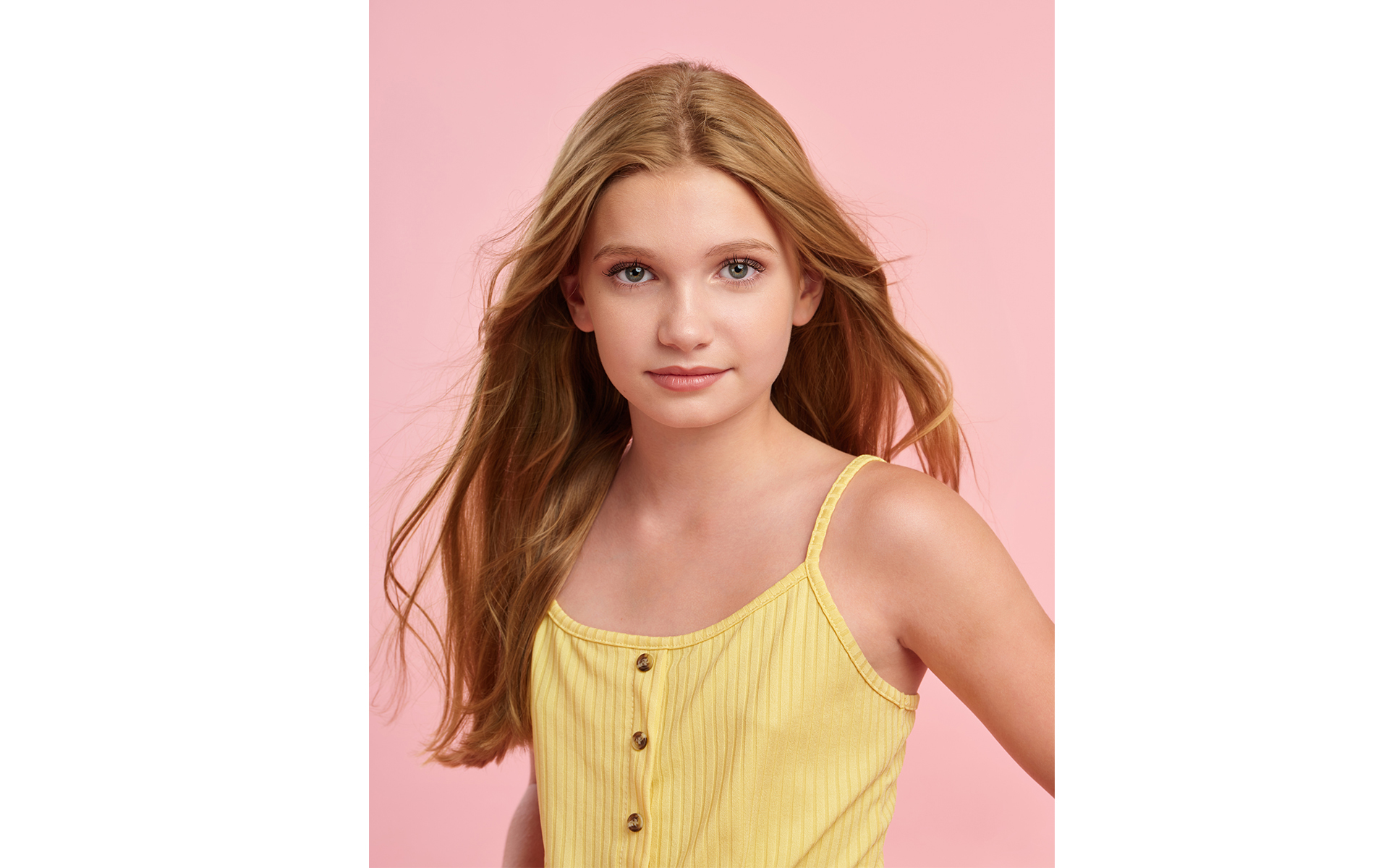 Blonde teenage model wearing yellow top front of pink backdrop fashion  brand photo shoot