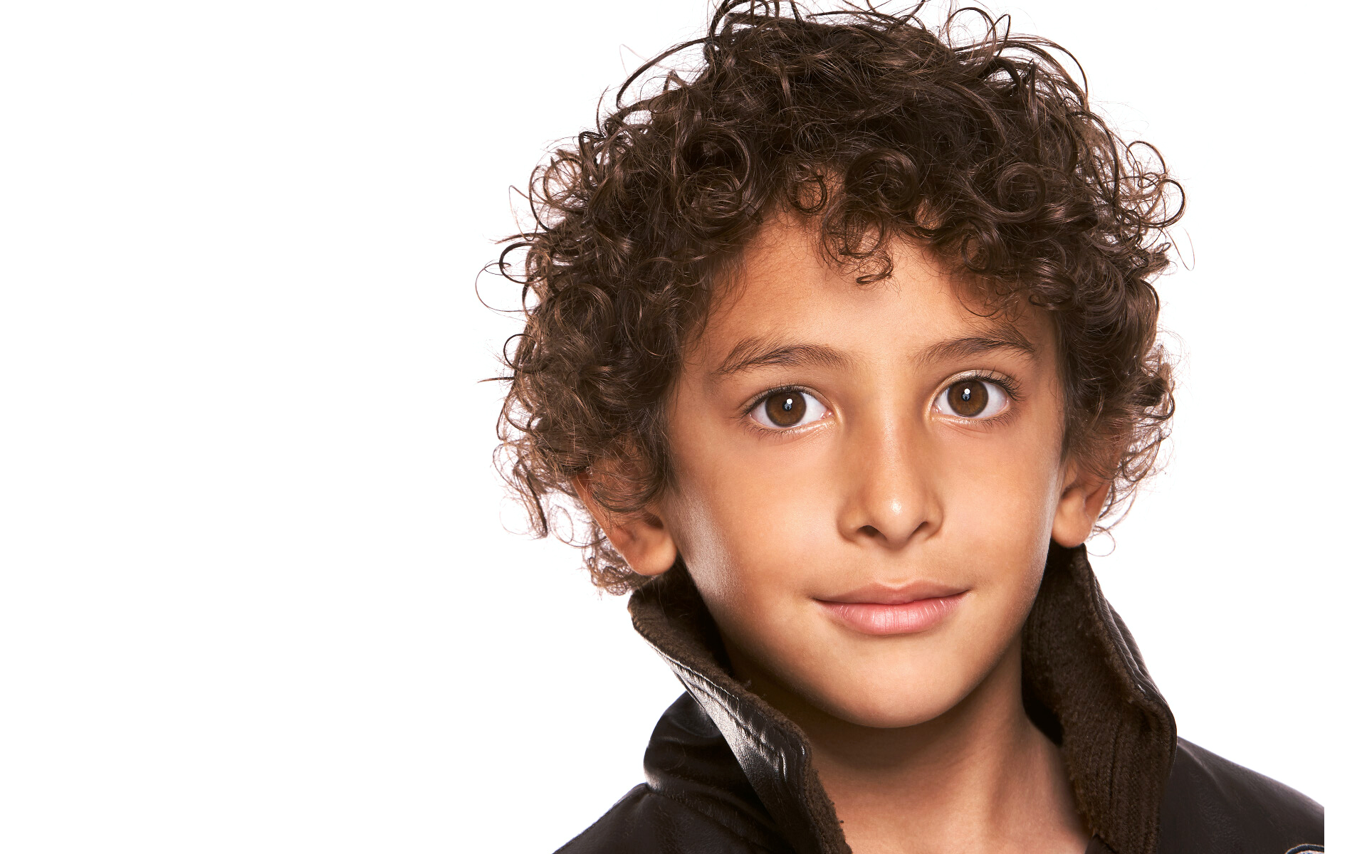 Portrait of young boy model wearing brown leather coat in front of white backdrop photo shoot