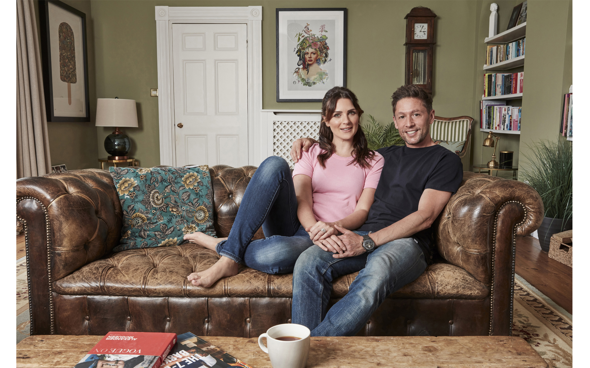 Man and woman sitting on leather sofa in their lounge for photo shoot for magazine
